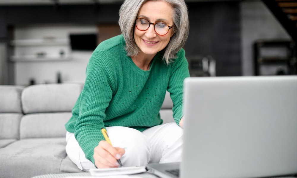 A woman smiling and writing in her modern home as she focuses on tax-optimized retirement planning and wealth management