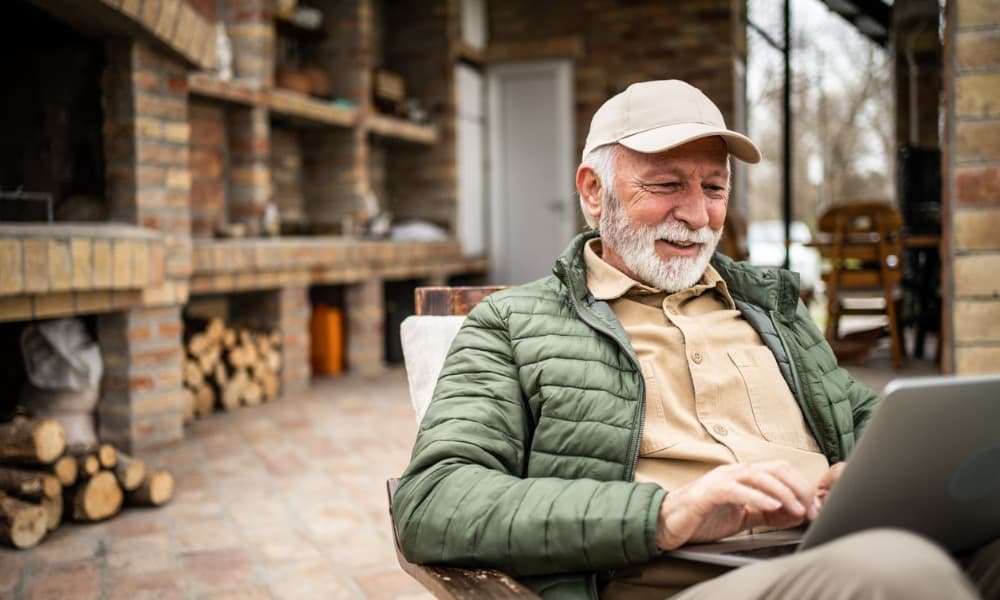 an older man sitting outside and using a laptop to plan retirement investments