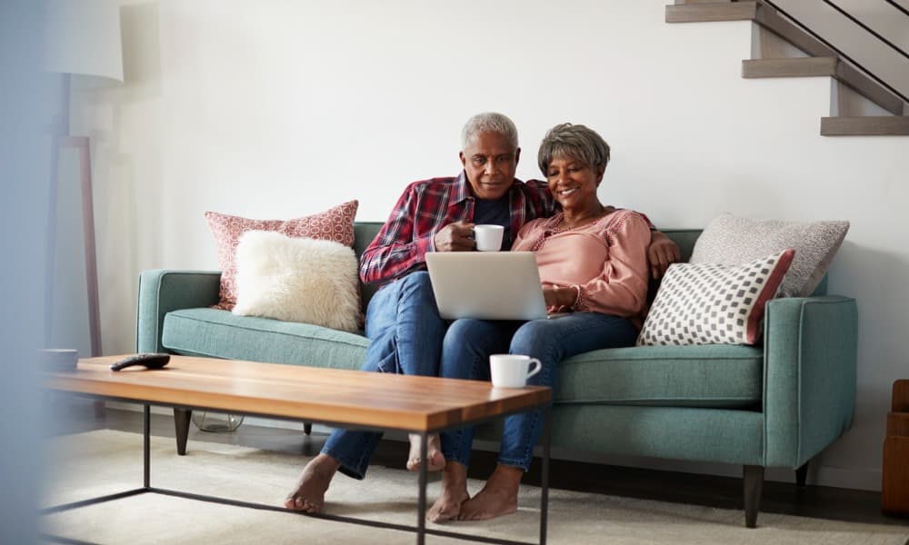A couple working together on a laptop on their couch and talking about estate planning