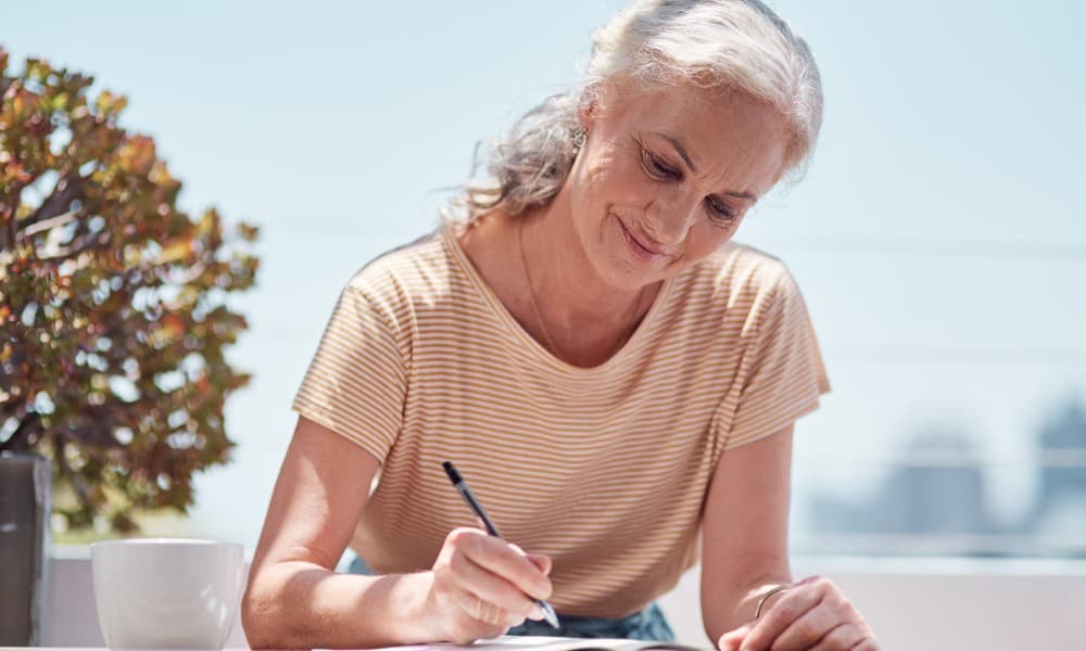 A smiling older woman sitting outside and drafting an advance directive