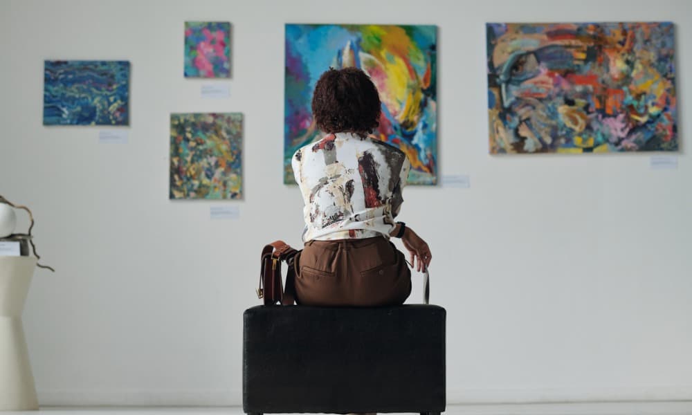 A woman at an art gallery looks at painting alternative investments