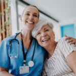 a smiling woman hugging a healthcare provider in scrubs and discussing healthcare costs