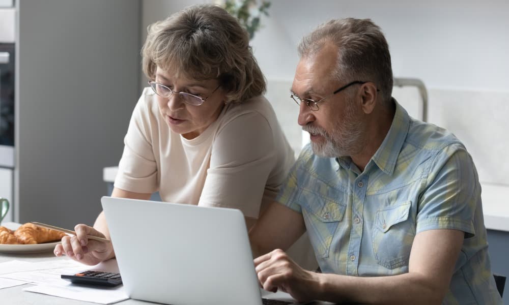 a couple reviewing insurance options at home with a laptop and calculator