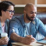 A couple going over finances together and conducting a cash flow analysis at a desk with a laptop and notebooks.