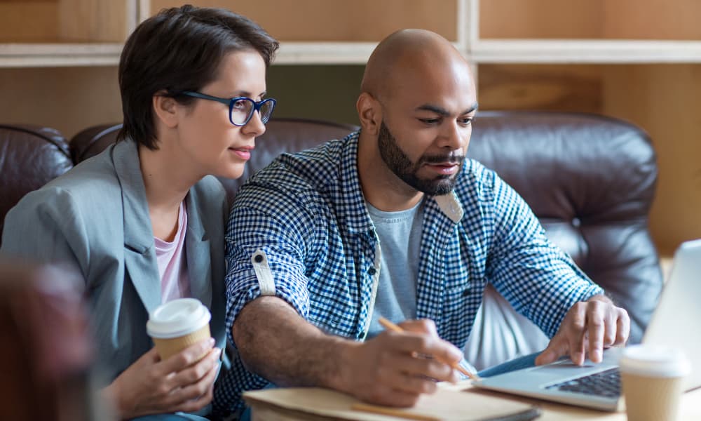 A couple going over finances together and conducting a cash flow analysis at a desk with a laptop and notebooks.