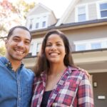 A couple in front of a home thinking about refinancing their mortgage.