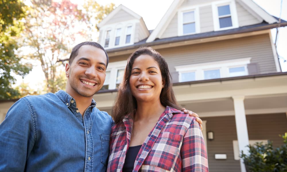 A couple in front of a home thinking about refinancing their mortgage.