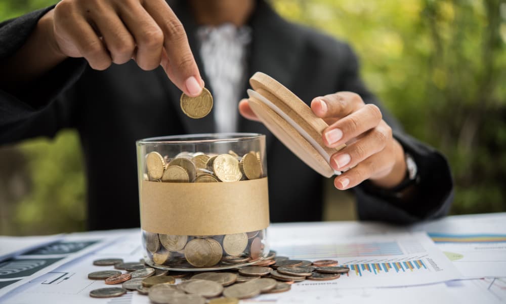 A man putting coins into a jar to save for retirement and college.