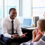 A financial advisor talking to a mother and daughter about education planning.