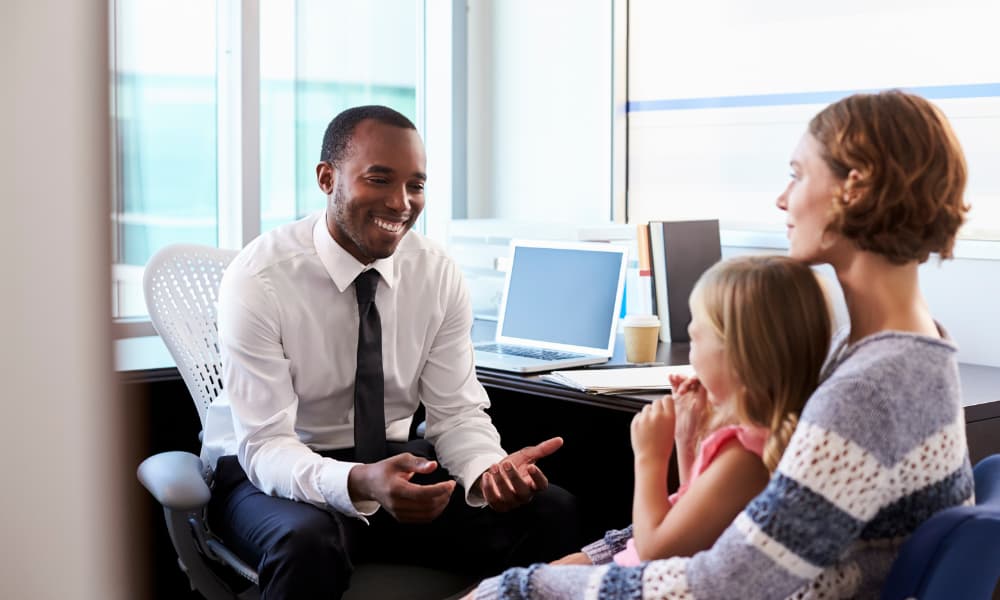 A financial advisor talking to a mother and daughter about education planning.