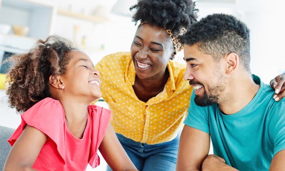 A family smiling and talking about life insurance for education planning.