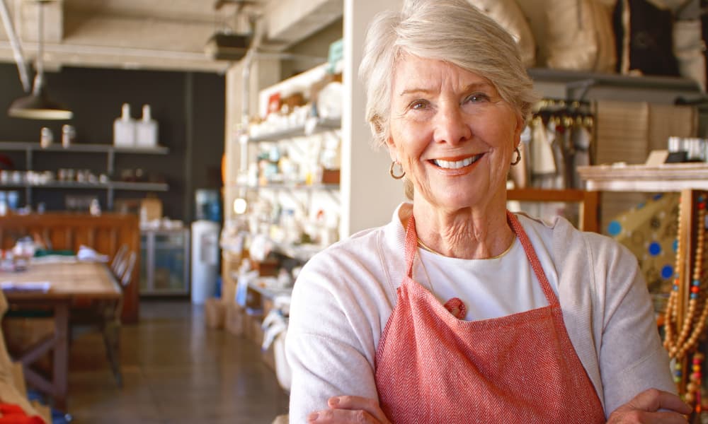 A business owner nearing retirement poses for a picture inside their retail business.