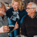 Happy adults enjoying coffee together in a warm café, representing long-term peace of mind from time in the market investing.