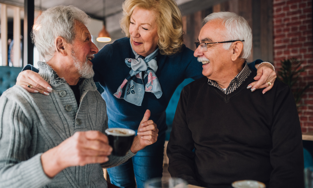 Happy adults enjoying coffee together in a warm café, representing long-term peace of mind from time in the market investing.