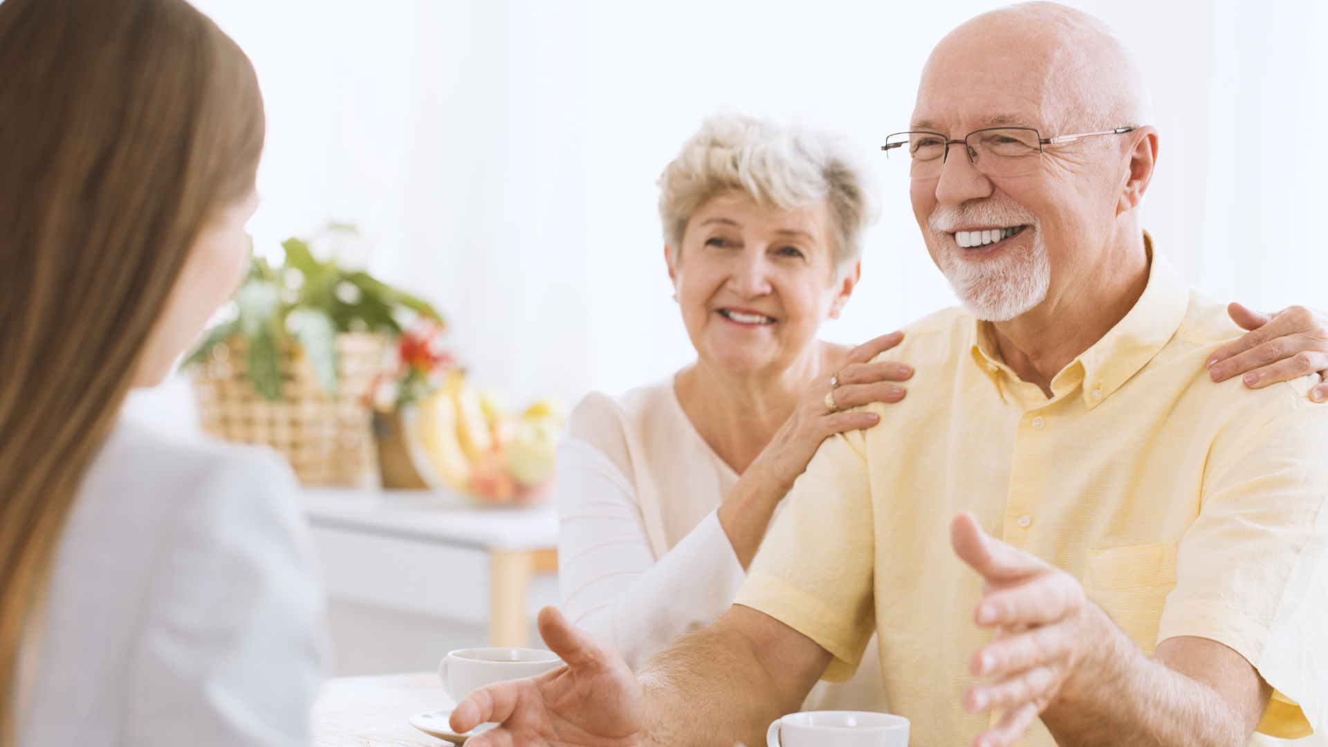 Elderly couple smiling and discussing financial planning strategies with their advisor about tax-loss harvesting before year-end.