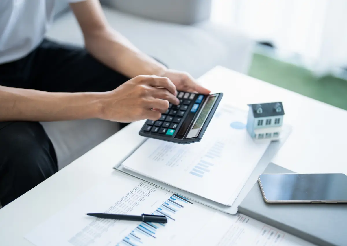Person calculating finances and using a laptop to plan college savings and tax deductions.