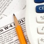 Financial advisor reviewing tax return and IRS Form W-4 to adjust withholding and plan post-filing tax strategy for 2026.