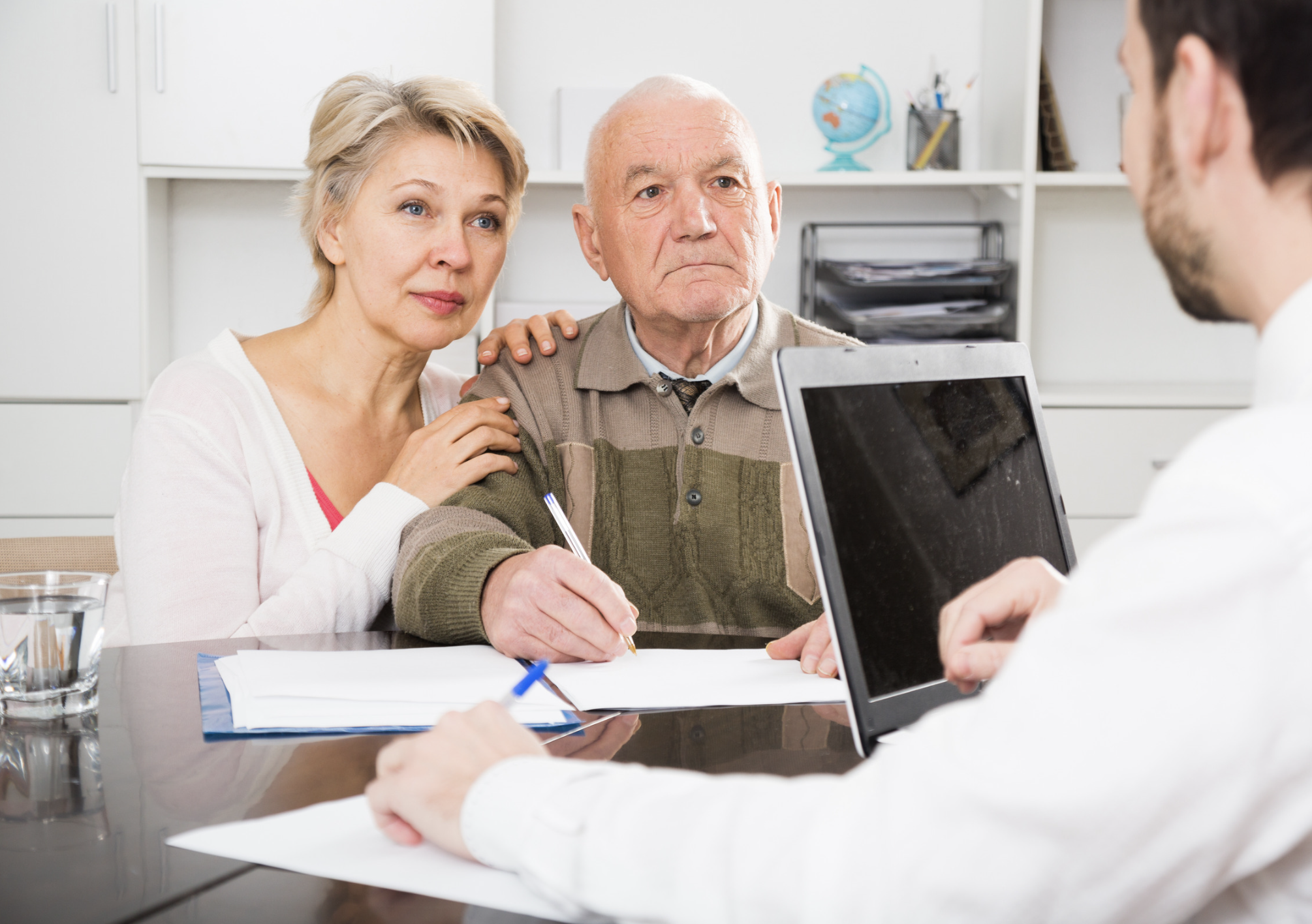 Older couple meeting with financial advisor to review estate planning documents and beneficiary decisions.