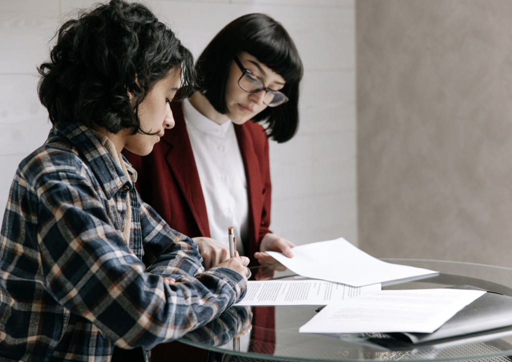 Advisor reviewing documents with a client signing paperwork, illustrating financial planning and beneficiary designation updates.