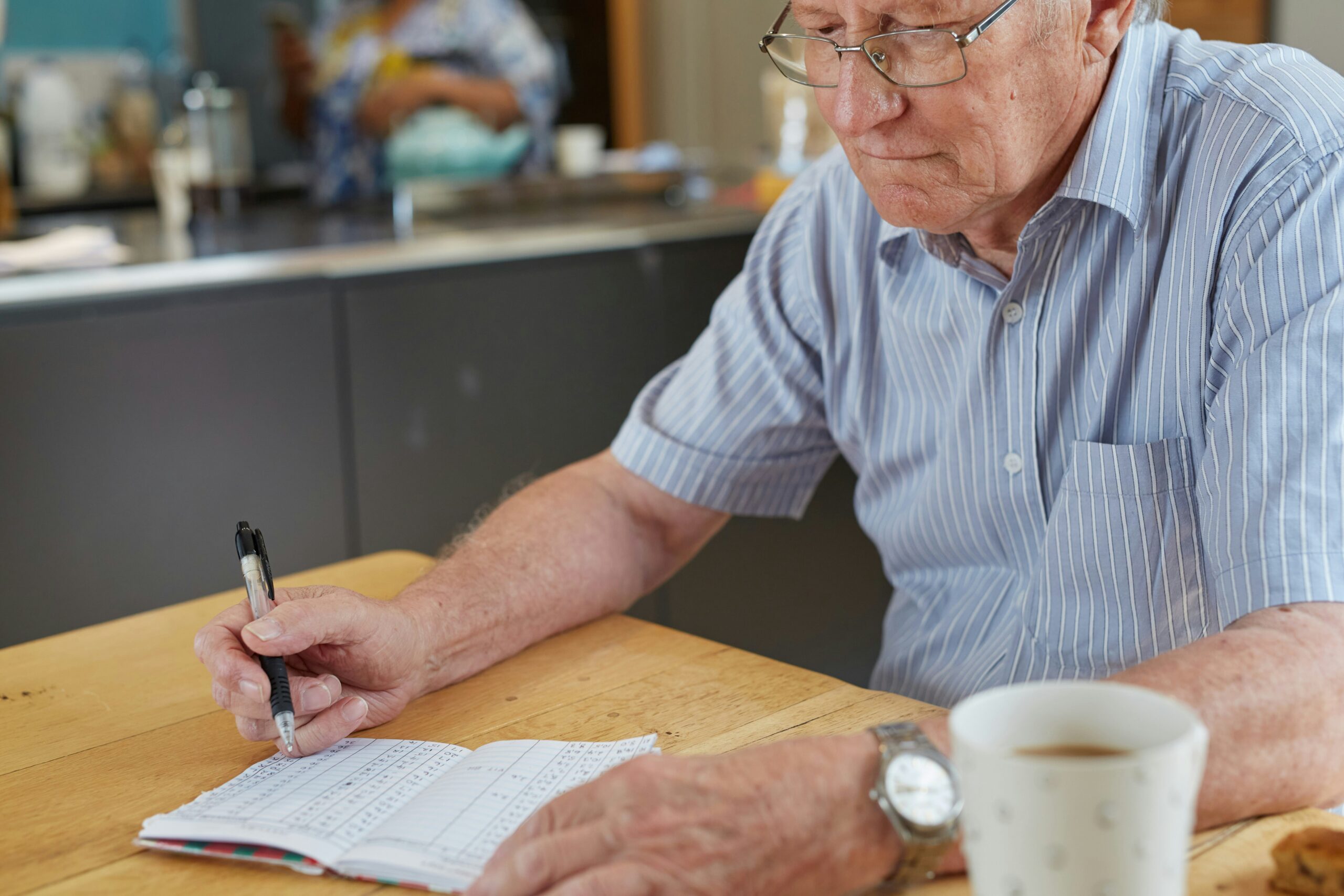 Senior man reviewing retirement finances and writing budget notes at home